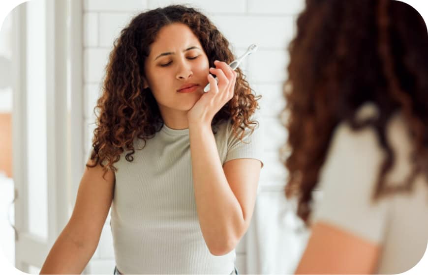 Young woman experiencing dental discomfort during a consultation at Enamelle Dental.